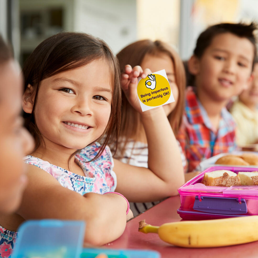 Schoolgirl proudly showing a Little Change Creators lunchbox card.